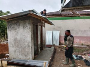 Warga Kompak Gotong-Royong Bersama Satgas TMMD Kodim 0416/Bute Memasang Atap Seng MKC MI Nurul Falah